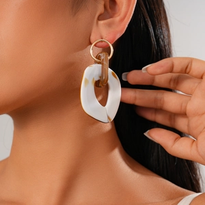 Close-up of white and brown tortoiseshell acetate hoop earrings on a fashion model
