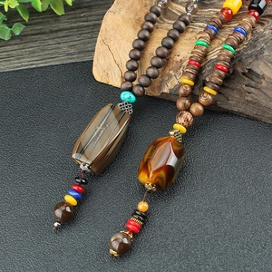 Ethnic vintage wooden bead necklaces with agate and amber pendants on wood background