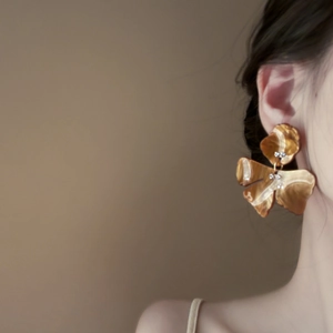 Elegant floral amber resin earrings with micro rhinestones worn by a model in warm light
