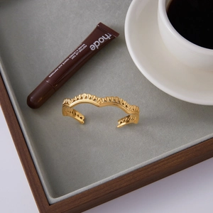 Dettaglio del bracciale dorato martellato con superficie ondulata e trame incise