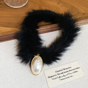 Detail of elegant black faux fur necklace with a large teardrop pearl pendant