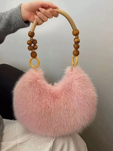 Detailed close-up of pink plush handbag with distinctive large wooden bead handle