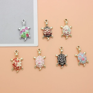 Detail of seven colorful enamel turtle charms with floral patterns and gold-silver finish