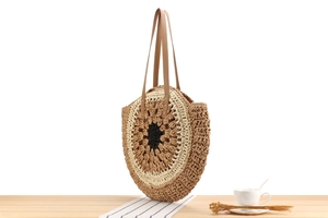 Detail view of a circular hand-woven paper straw shoulder bag with multi-color spiral pattern