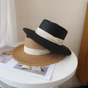 Detail of woven straw texture and cream ribbon on classic flat top boater hats