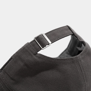 Detail of adjustable metal buckle and stitching on dark gray cotton baseball cap