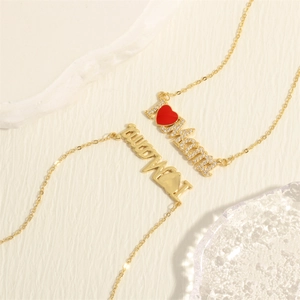 Macro detail of 18K gold-plated Mama necklaces with inlaid crystals and red heart pendant
