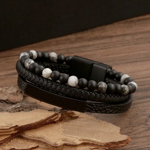 Braided leather bracelet with matte black and marble beads on a natural wood base