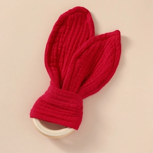 Close-up of red cotton muslin bunny ears on a smooth natural wooden baby teething ring
