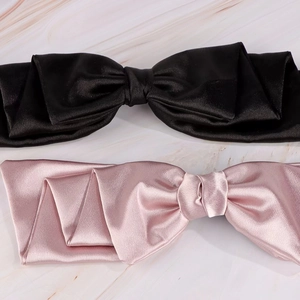 Detailed view of pink and black satin hair clips displayed on a marble surface