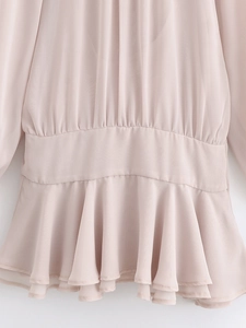Detailed close-up of light pink pleated chiffon dress with ruffled hem and airy texture