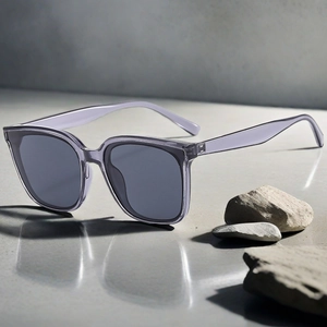Détail de lunettes de soleil carrées oversize avec monture violette sur pierre naturelle