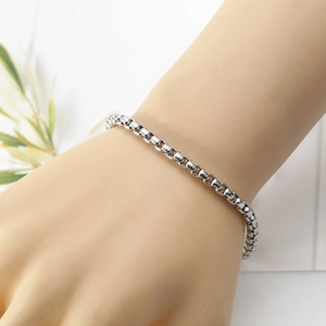 Detailed view of silver stainless steel box chain bracelet worn on a wrist