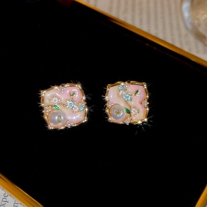 Macro detail of elegant pink enamel earrings with tiny pearls and gold floral patterns
