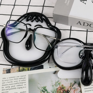 Modern eyeglasses frame displayed on a decorative cartoon face silicone storage tray