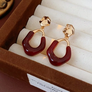 Macro shot of oval dark red resin earrings in a luxury velvet box with gold details
