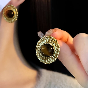 Gros plan de boucles d'oreilles fleurs vintage avec œil de tigre et détails cristal