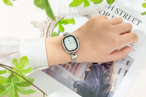 Detail of elegant silver mesh strap ladies watch with oval rhinestone bezel on a model wrist
