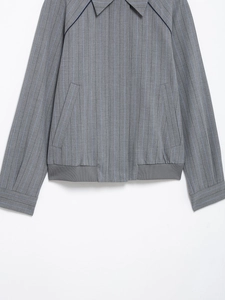 Detail of ribbed hem and side pocket on a grey striped bomber jacket with a clean finish