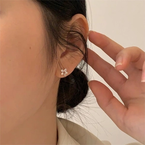 Detailed close-up of 925 sterling silver flower stud earring worn on model's ear