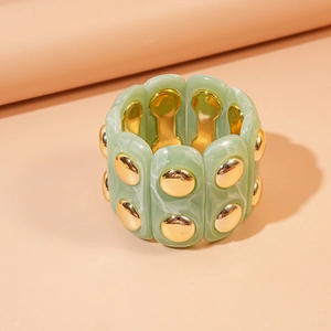 Detail of wide stretch bracelet featuring green marble resin and gold metal studs
