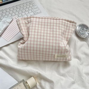 Detail of pink and white checkered fabric storage bag with Sozakka label on soft white linen