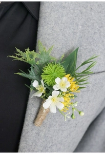 Detail of faux white boutonniere with green leaves and twine on a grey suit jacket