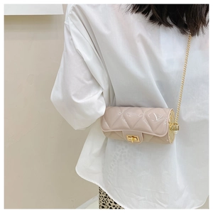 Detail of beige quilted cylindrical bag with gold twist lock and pearl chain strap