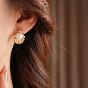 Elegant pearl stud earrings with zircon accents and gold plating worn by a model