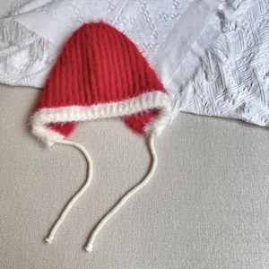 Detail of plush knitted earflap hat with contrast red and cream fluffy faux fur texture