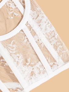 Close-up of white lace corset detail featuring structured boning and floral patterns