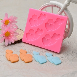 Dettaglio macro dello stampo in silicone rosa con quattro cavità a cuore e modelli