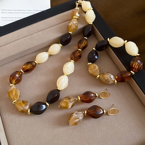 Detailed macro view of vintage acrylic jewelry set with amber resin beads and gold spacers