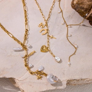 Detailed flat lay of layered gold necklaces with shell, starfish, and heart pendants