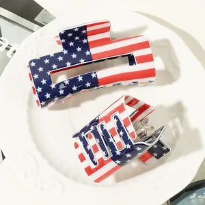 Close-up of two large American flag hair claws with red stripes and blue stars on a ceramic tray