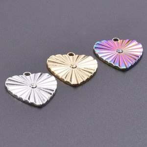 Macro shot of heart pendants in gold, silver, and rainbow steel with sunburst texture