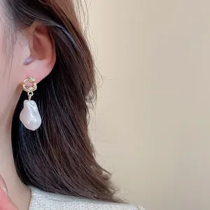 Detailed close-up of baroque pearl earrings with irregular gold rings on model