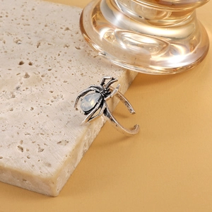 Macro detail of retro silver spider ring with opal stone on beige travertine stone