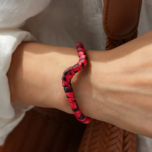 Detailed view of red and black spiral woven wrap bracelet worn on a model's wrist