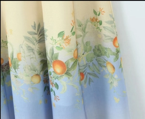 Detailed close-up of Bohemian summer dress fabric with orange and lemon botanical prints