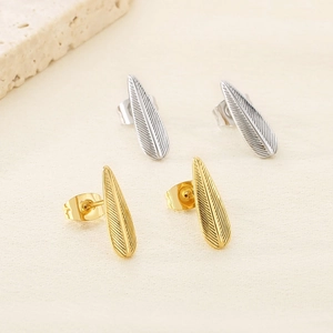 Détail macro de boucles d'oreilles plumes en acier inoxydable en fini or et argent