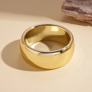 Close-up of a wide polished gold minimalist ring with smooth mirror finish surface