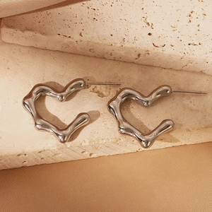 Detail shot of silver heart studs with wavy edges on stone and silk background