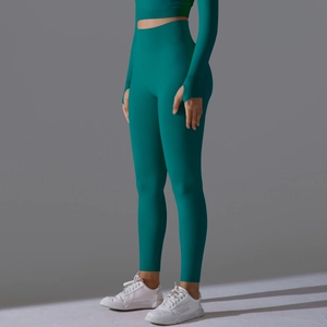 Detail of high-waist yoga pants with thumb-hole crop top in dark teal knit fabric