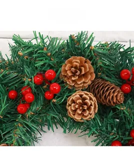 Gros plan d'une couronne de Noël avec des aiguilles de pin, des baies rouges et des cônes