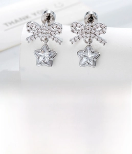 Detail of silver bow and star stud earrings with zircon inlay and titanium steel post
