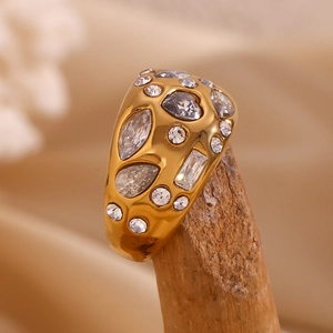 Macro detail of gold 18K plated ring with micro-set white gems on textured wood