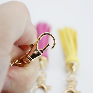 Hand holding a golden lobster clasp for handmade PU woven bag charm and keychain accessories