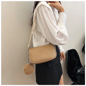 Detail view of beige woven texture crossbody bag with matching round coin purse charm