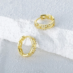 Macro shot of gold link hoop earring with sparkling white cubic zirconia on stone background